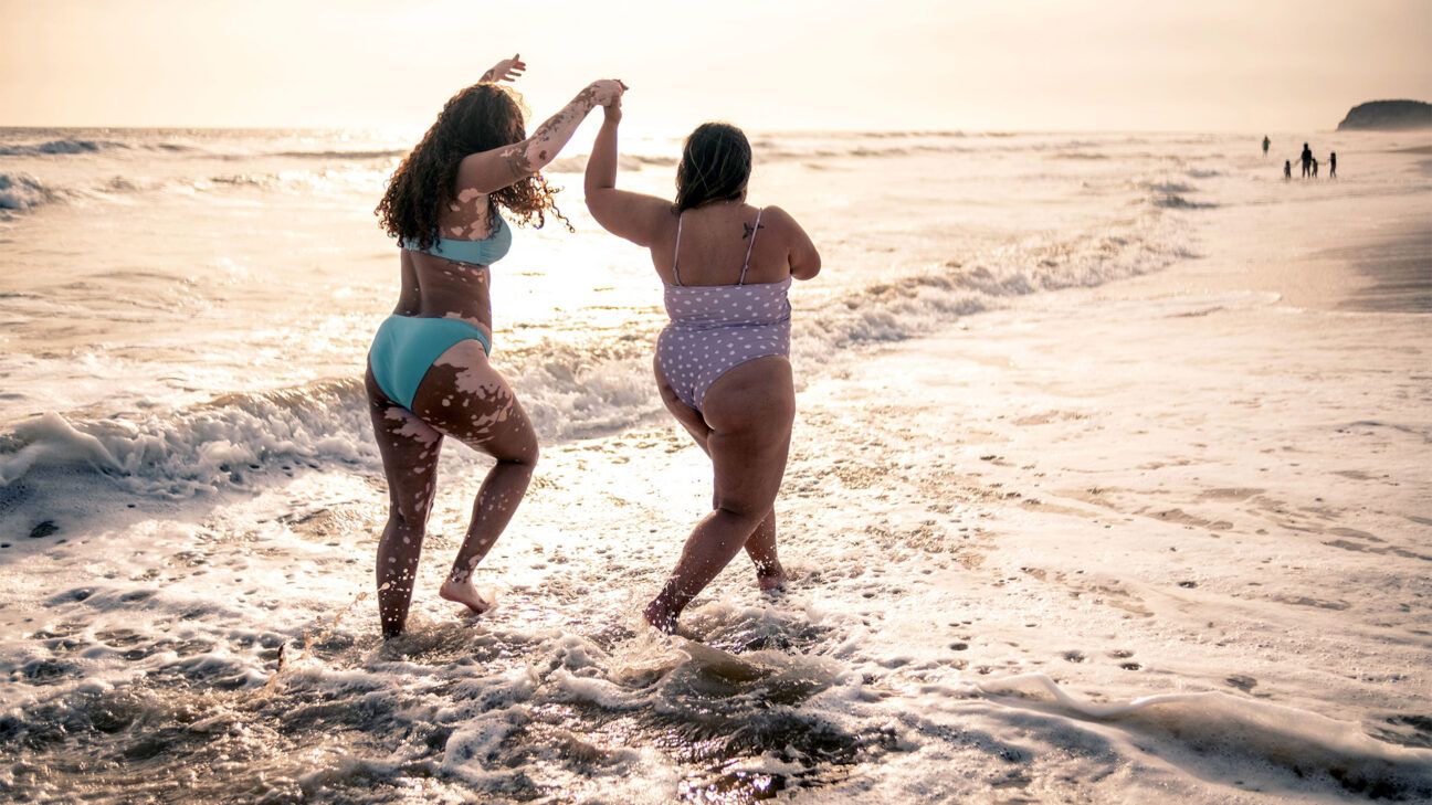 Two women in bikinis are seen on a beach.