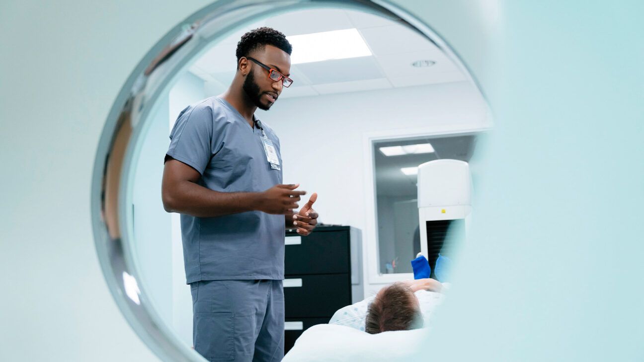 Healthcare provider speaks to a patient going into a MRI machine.