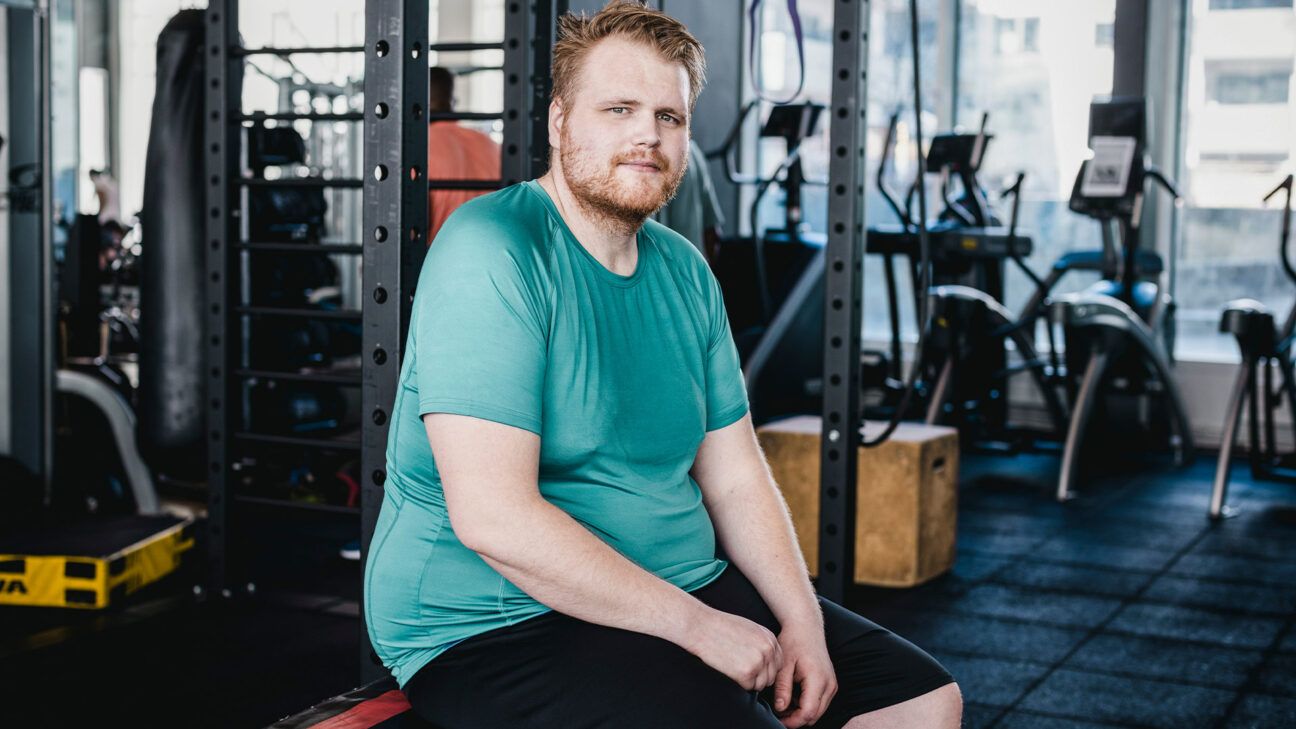 Man in green tshirt seen sitting on a bench at a gym.