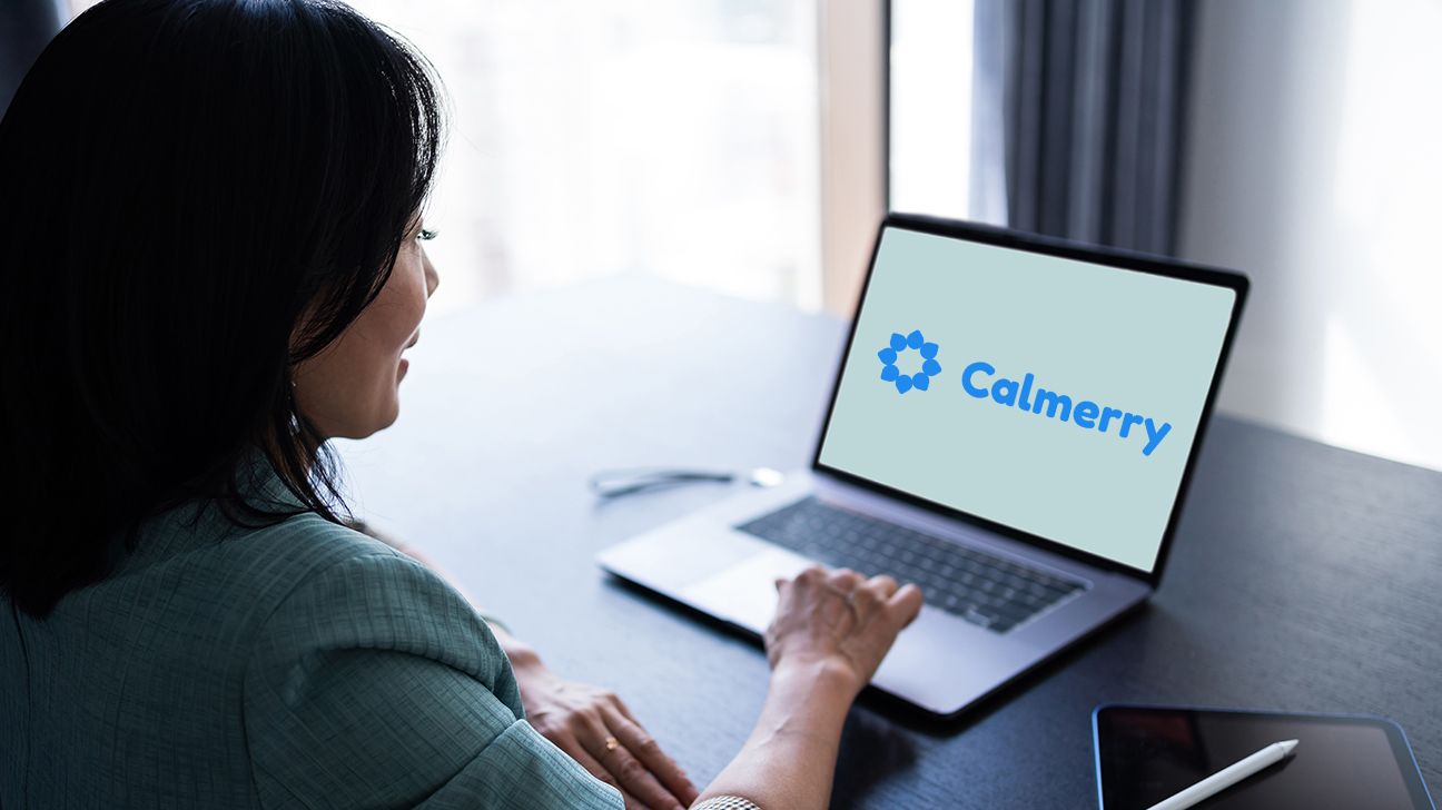 person sitting at table, laptop open in front of them. Calmerry and its logo is on the screen