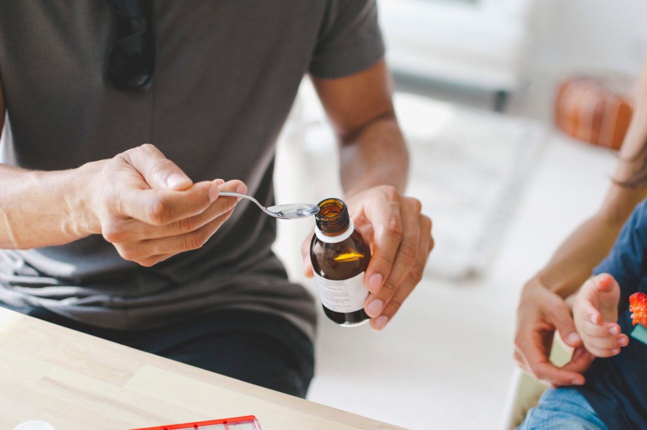 Person pouring castor oil onto a spoon.