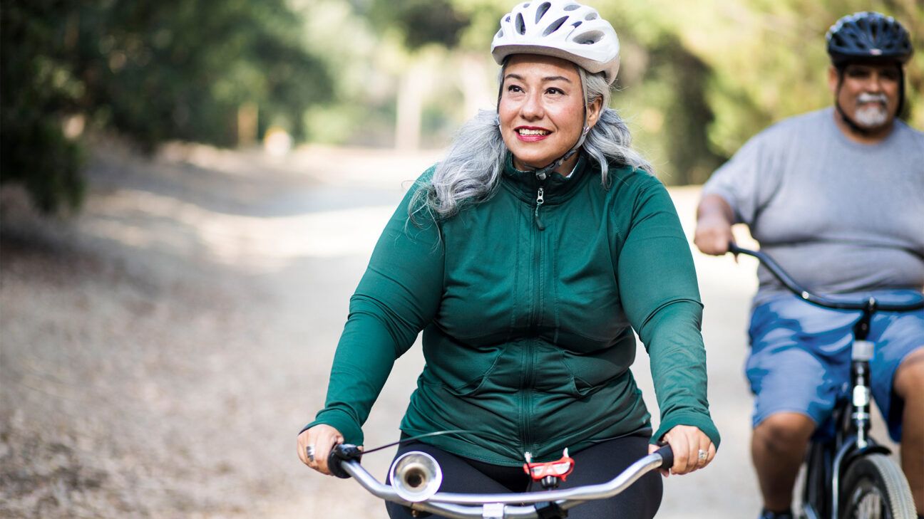 Woman in green jacket is seen biking.