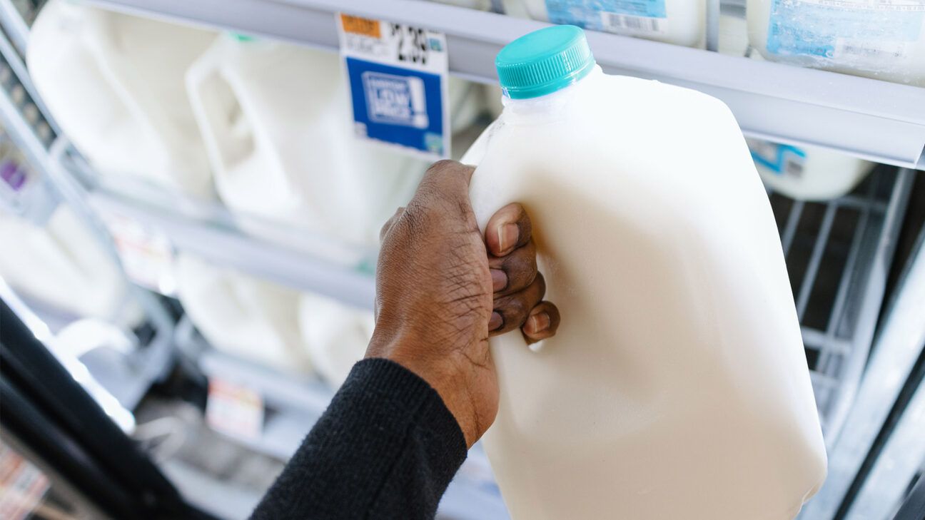 A person grabbing a gallon of milk.
