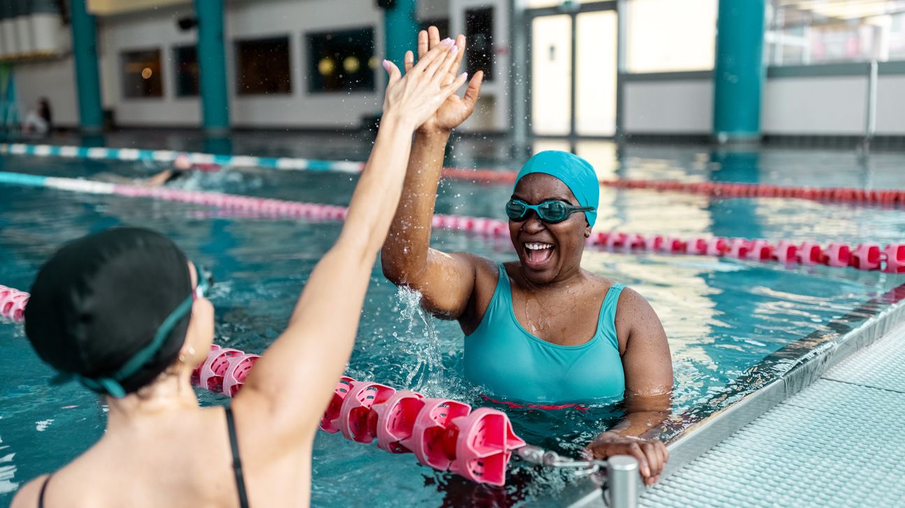 Two swimmers in a pool giving a high five.