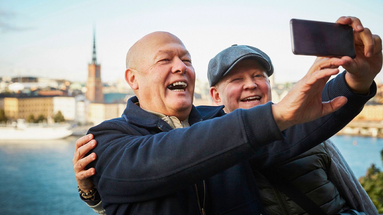 Elderly men smiling and taking a selfie.