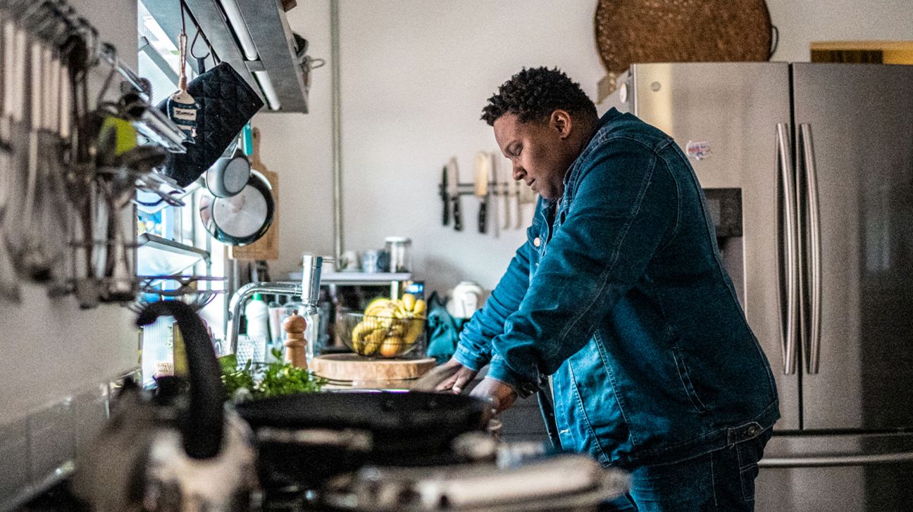 A man leaning over a kitchen counter.