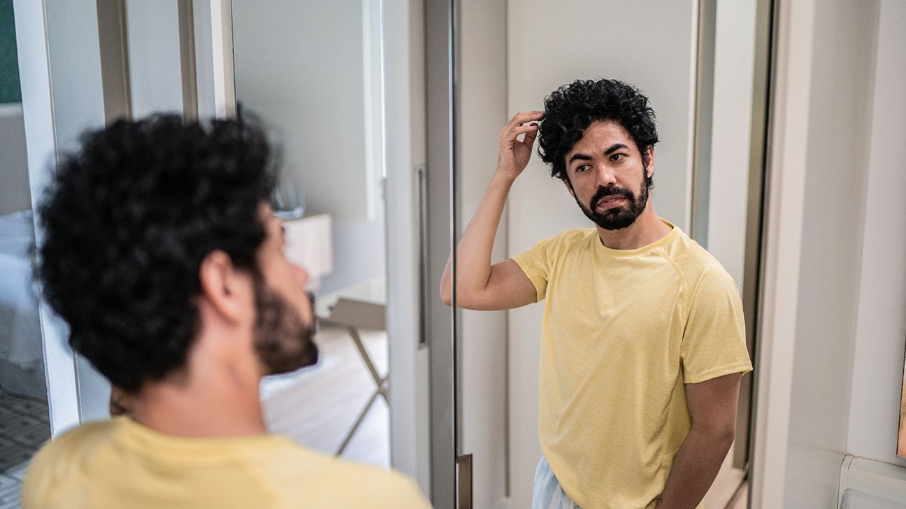 A man checking his appearance in the mirror.