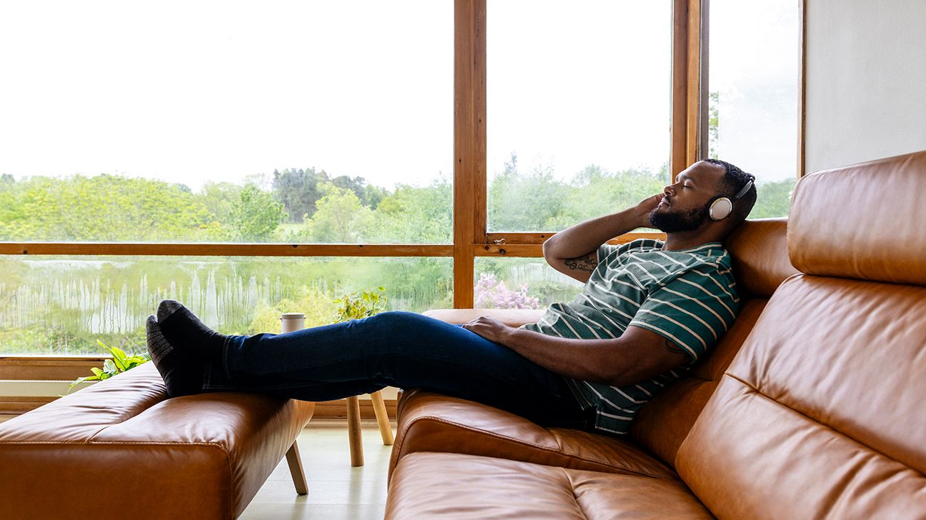 A man lying on a couch wearing headphones.