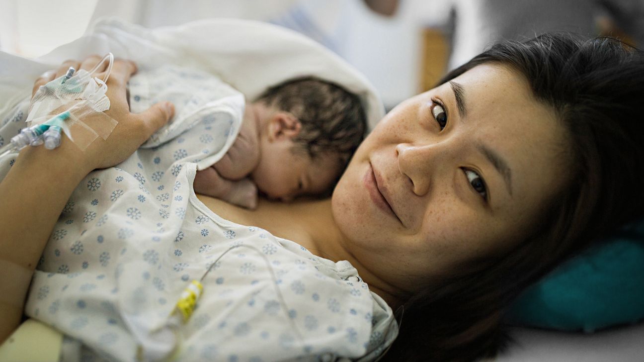 New mother holds newborn in hospital bed