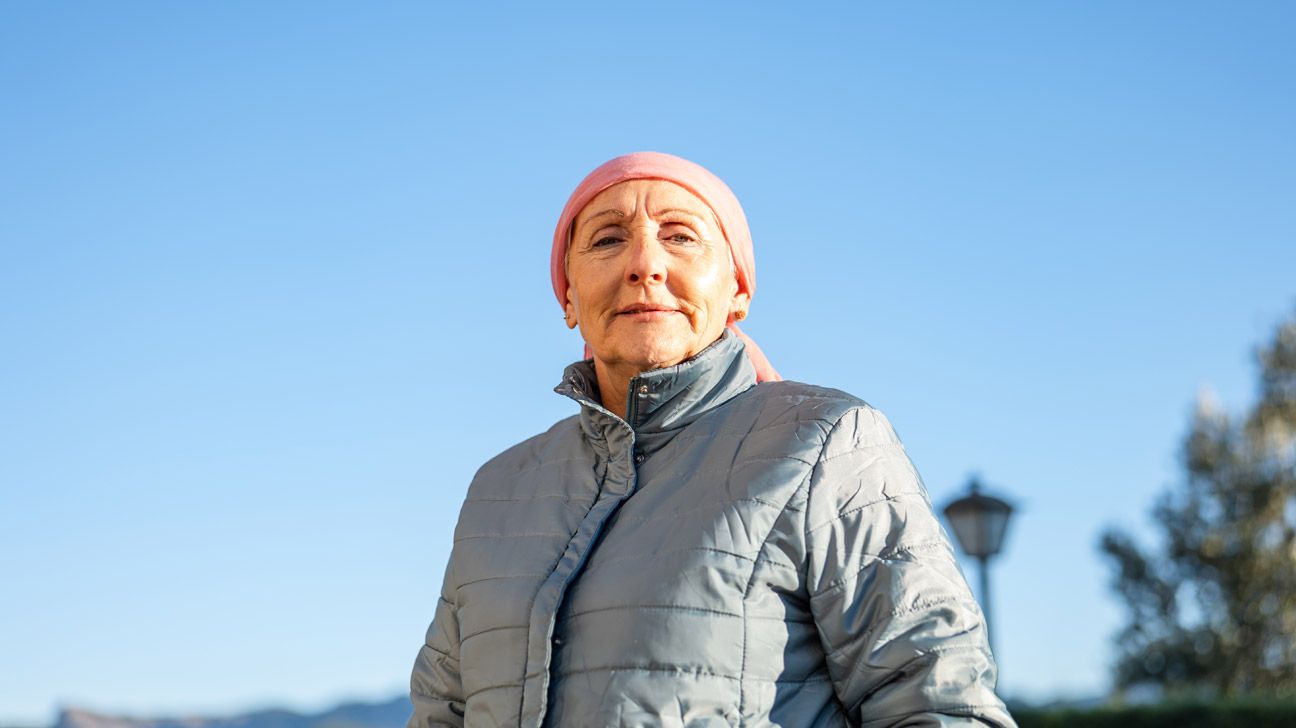 Older female adult standing outside wearing a winter coat and head wrap to depict stage 4 breast cancer.