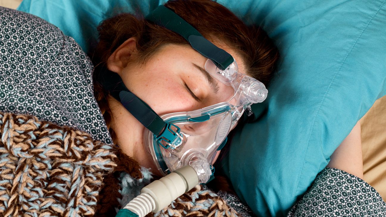Woman with CPAP machine in bed.