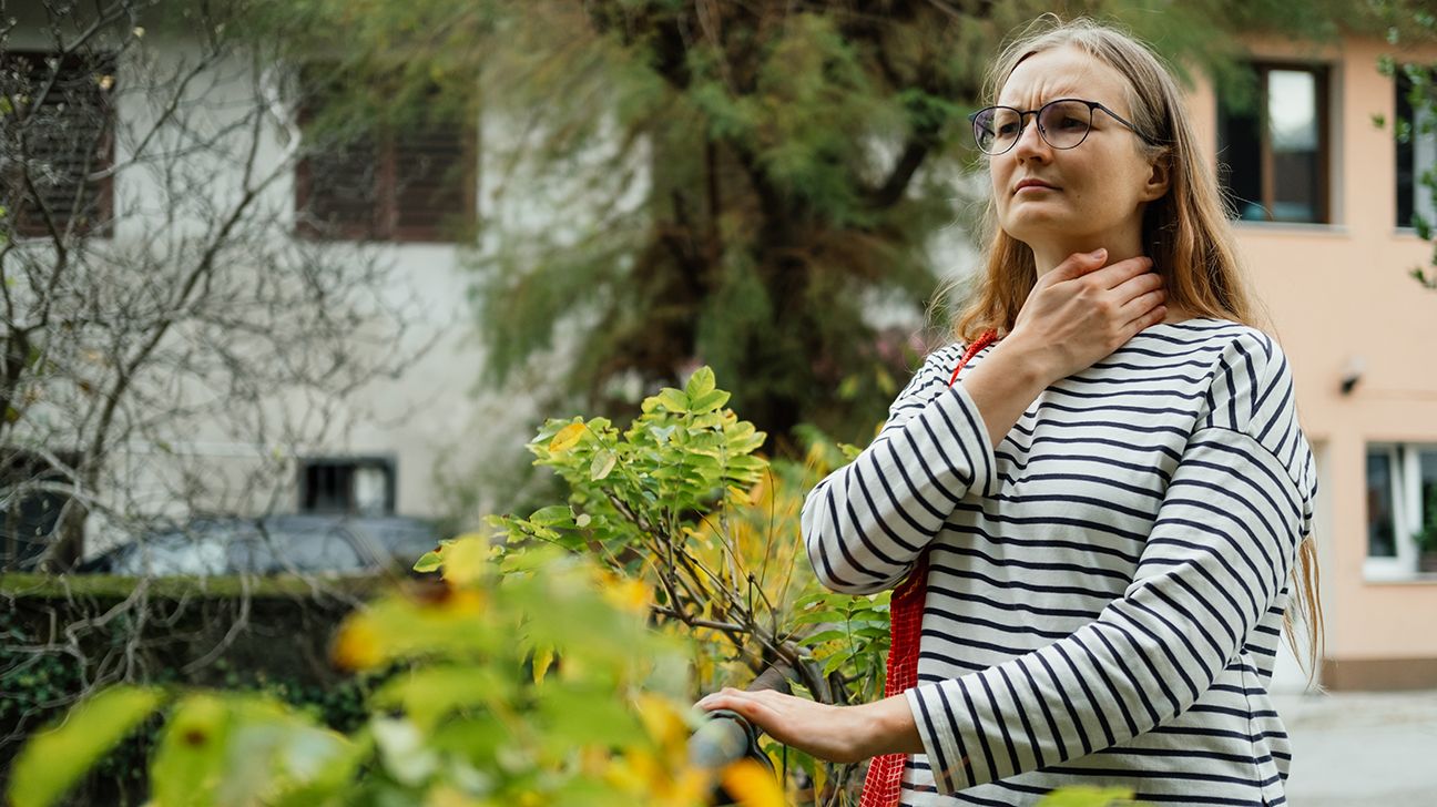 A woman touching her throat.