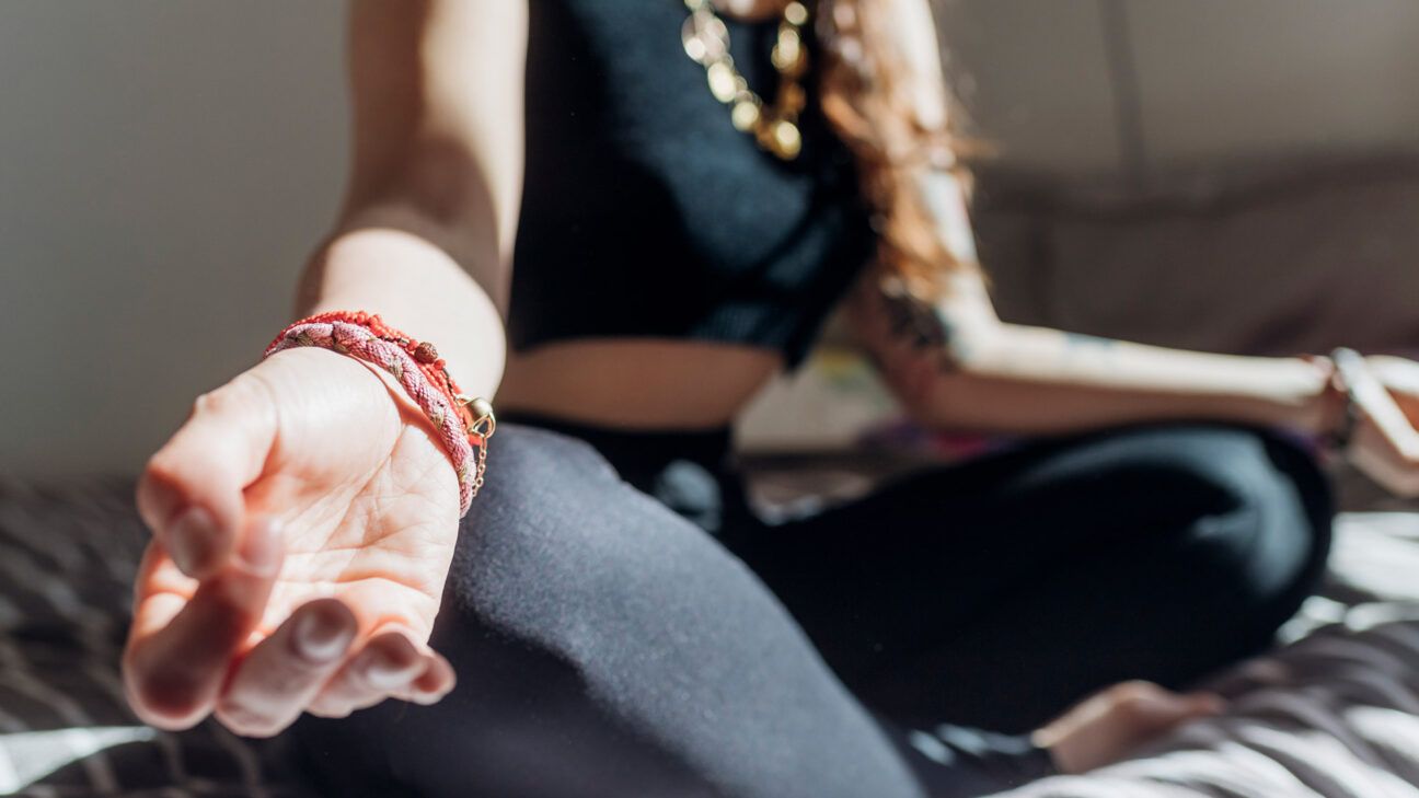 close up of hands of female meditating on bed