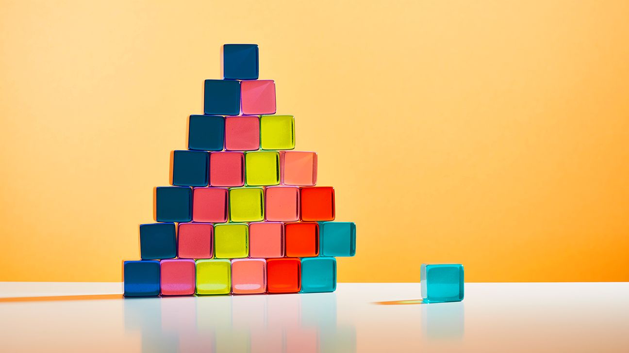 A nearly perfect pyramid of colorful glass blocks, with one at the bottom missing. 
