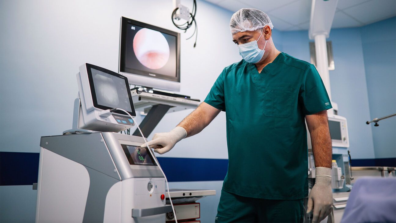 Physician prepares machine in operating room.