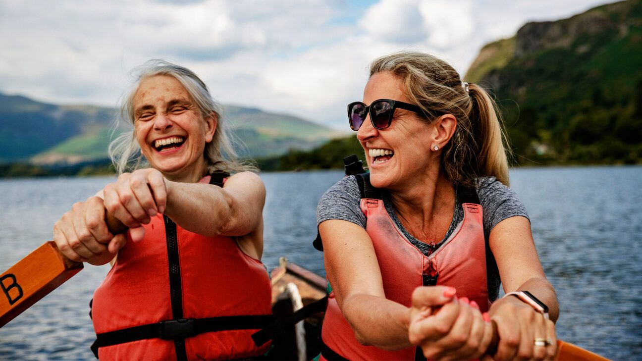 Two women paddle in a kayak on the water.