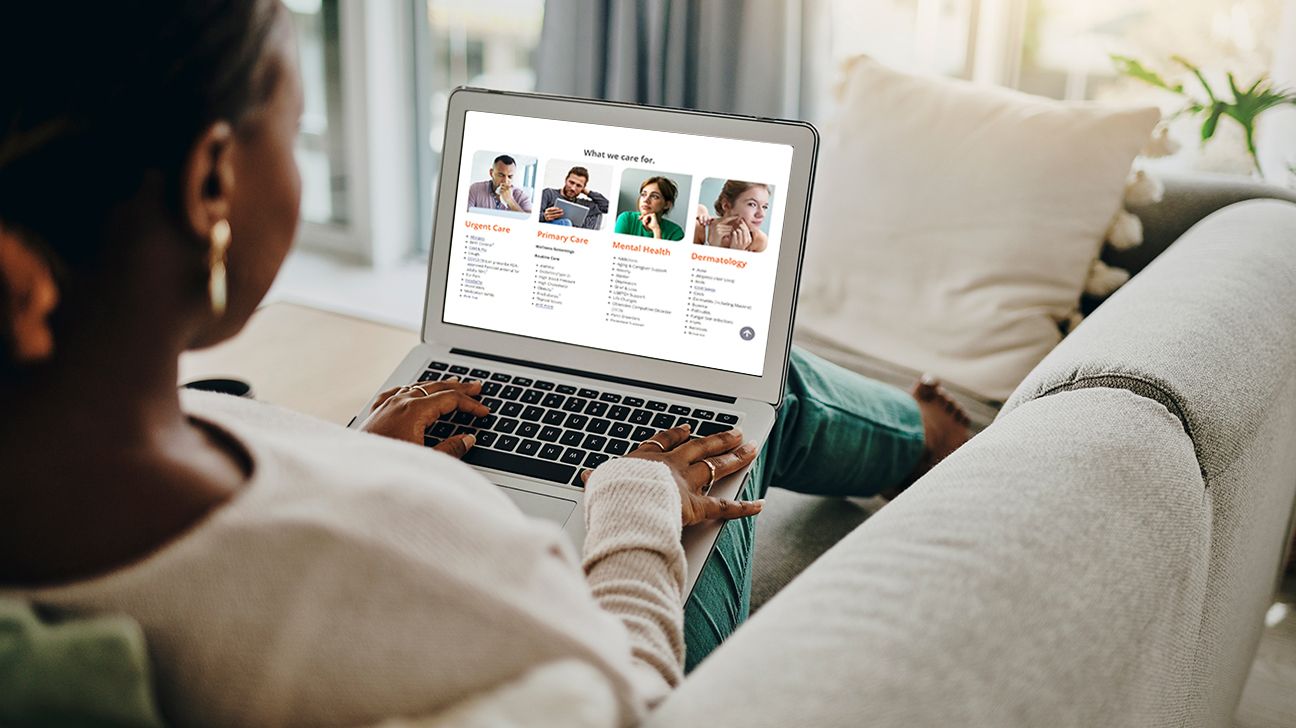 person is sitting on a sofa with a laptop in their lap. They are on MDLive's webpage, that lists the different types of services they offer. From the left: urgent care, primary care, mental health, and dermatology.