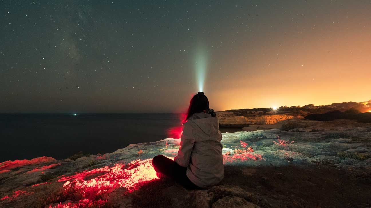 Someone sitting on the edge of sea, watching a comet. 