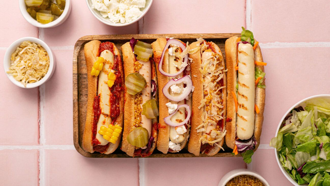 A row of five hot dogs with different condiments