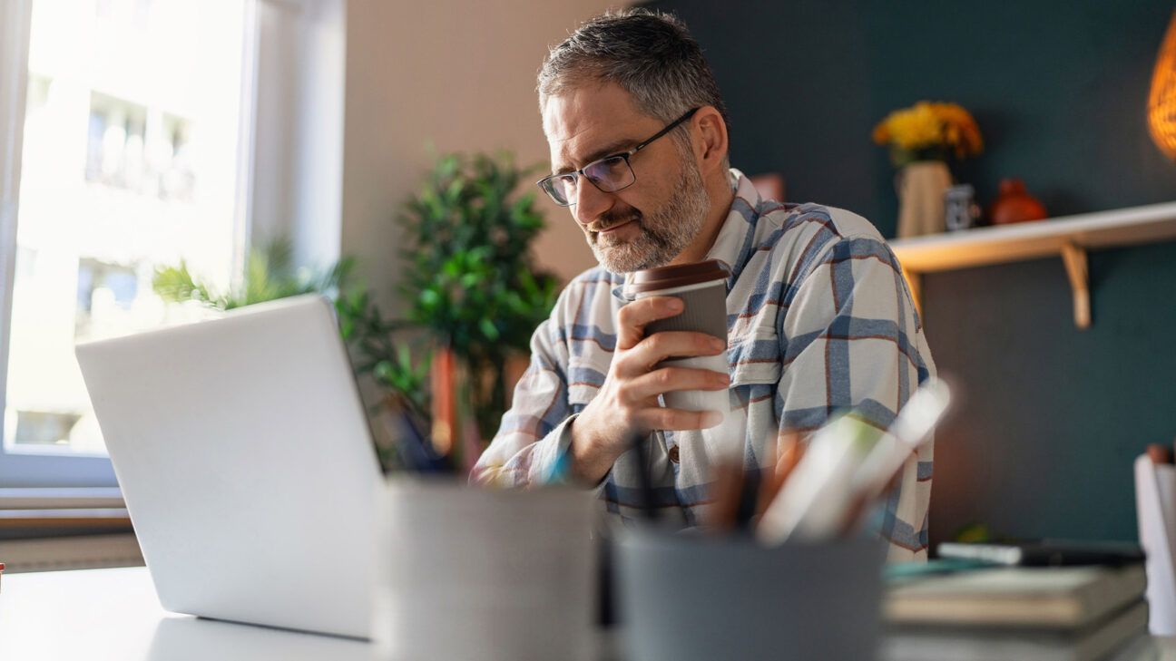 Man with a beard looks at a laptop.