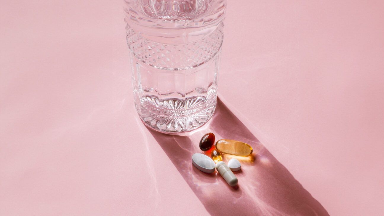 Pills next to a glass of water.