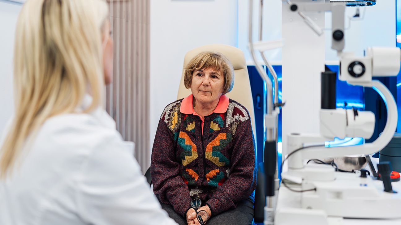 Older female speaking with an eye specialist in a clinical setting.