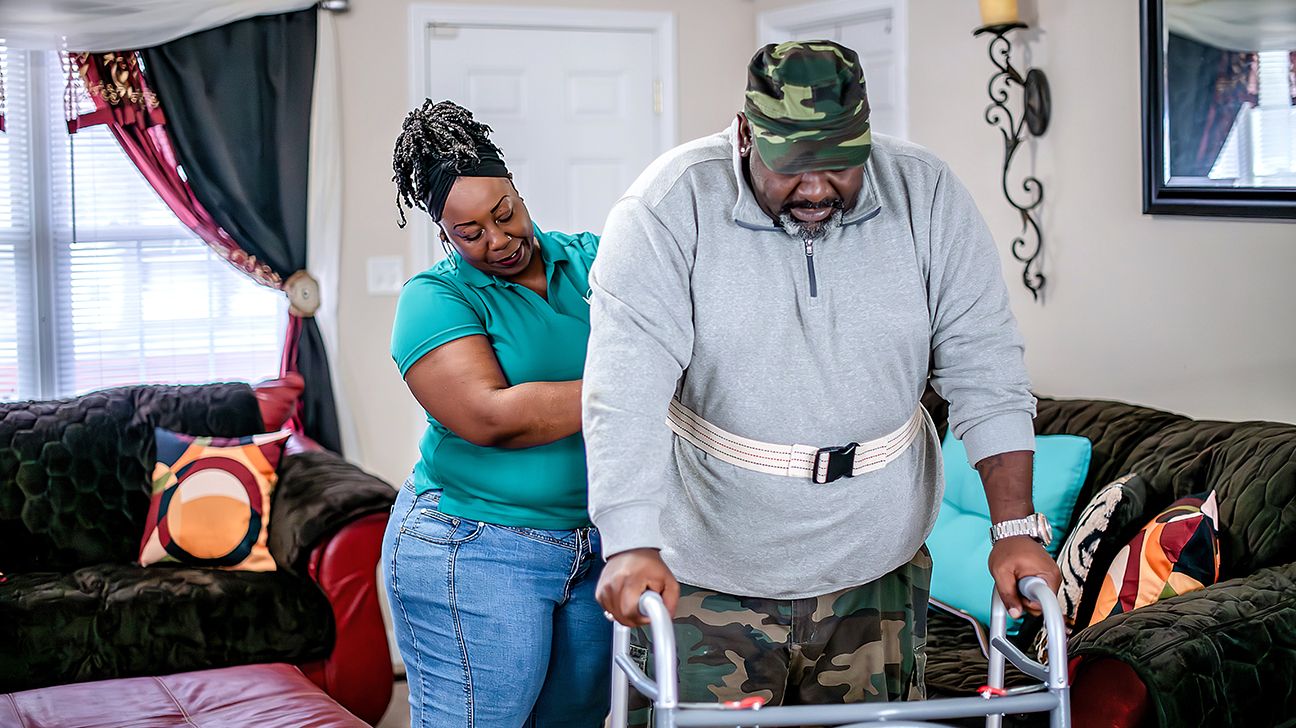 Woman caregiver helping veteran use walker
