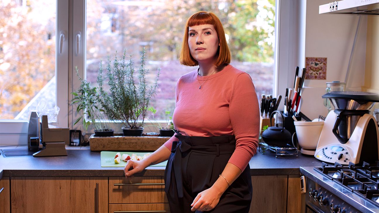 Young redhead woman stands in kitchen