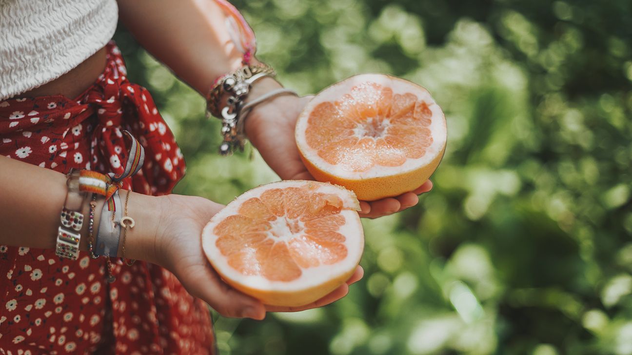 Woman holding two orange halves in hands