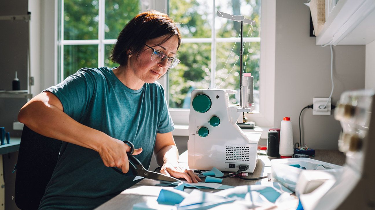 A woman with glasses using a sewing machine.