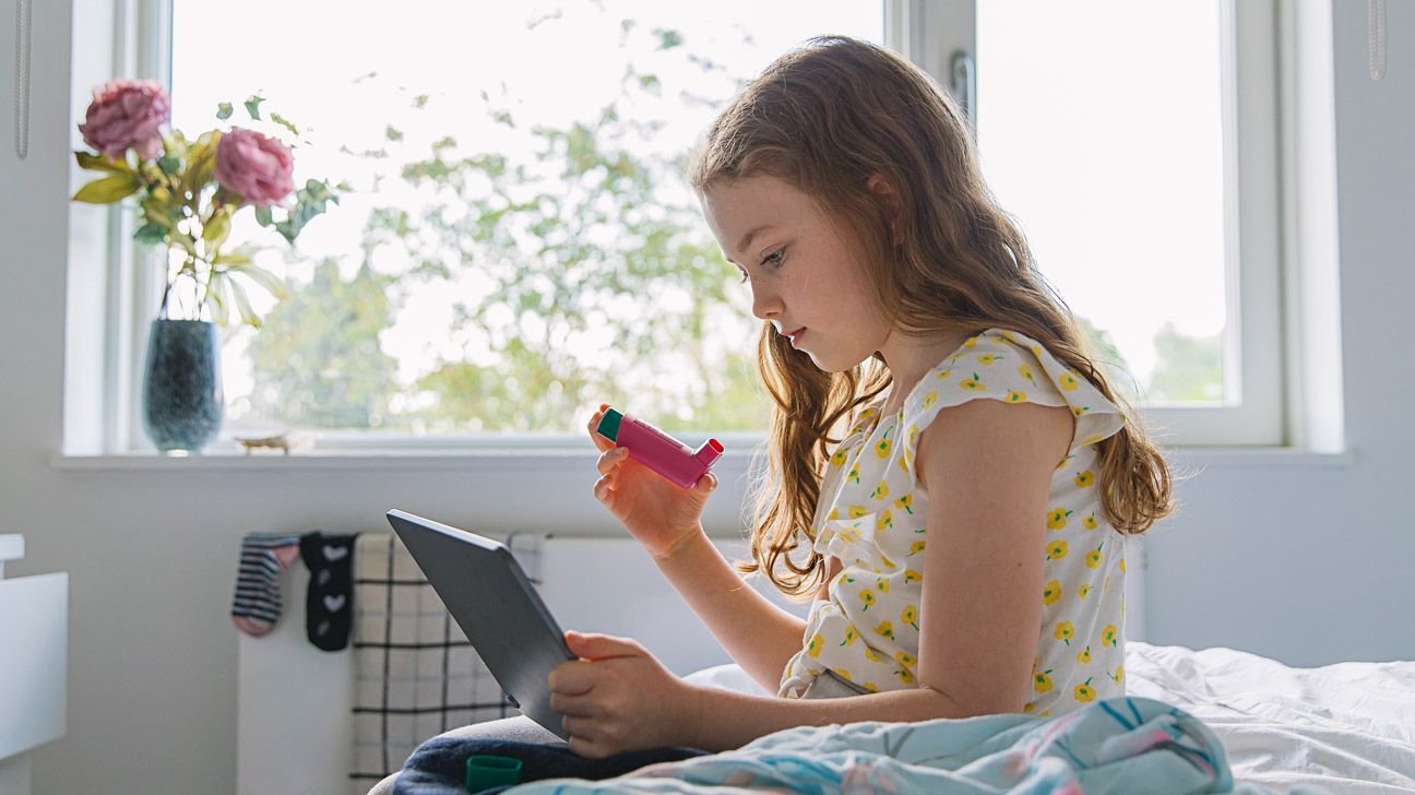 young girl holding her asthma inhaler and reading-1