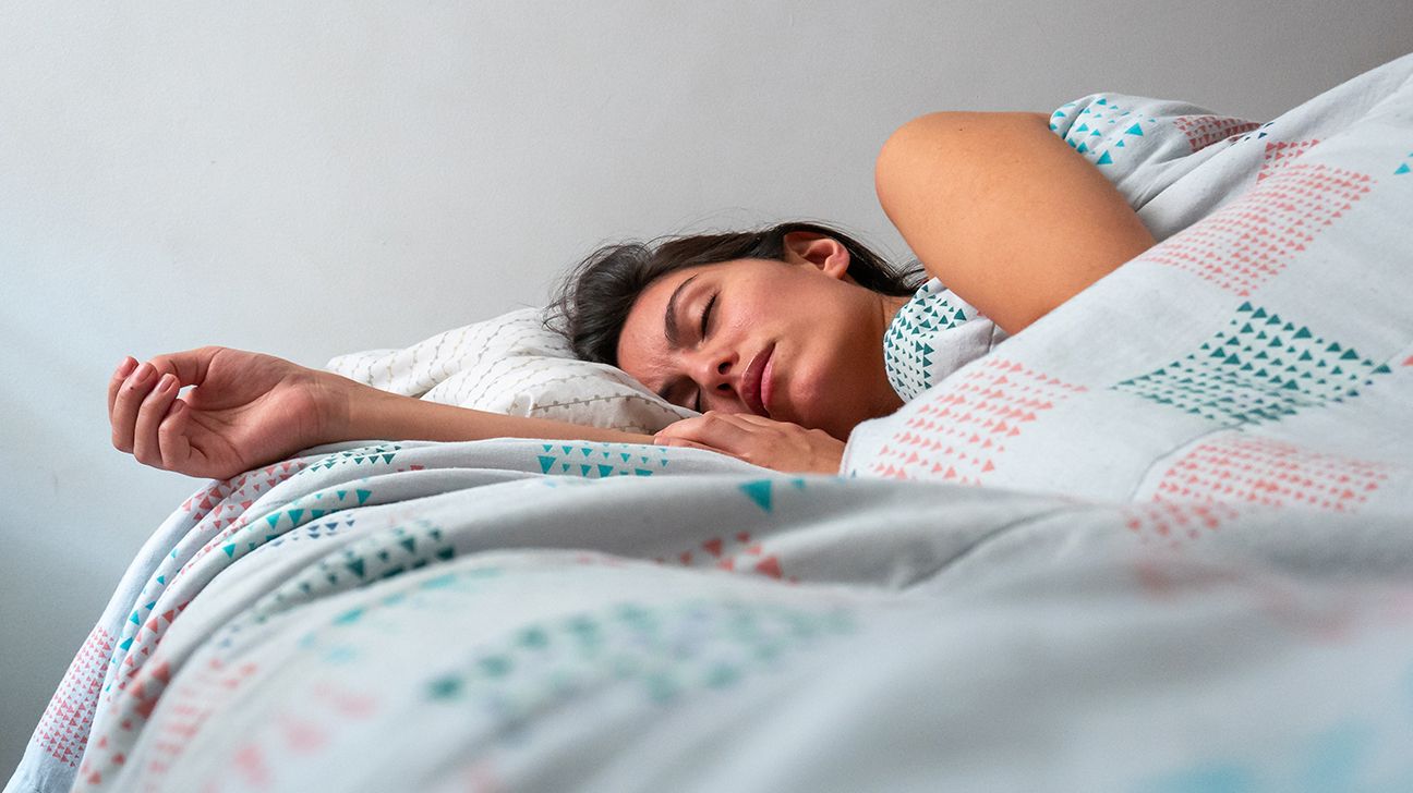 Female sleeping in bed under a checkered duvet.