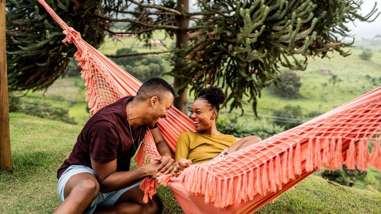A man and woman sitting in a hammock.