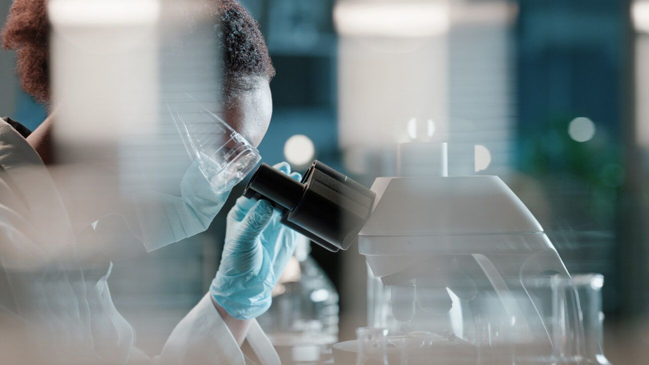 Female scientist looking into a microscope.