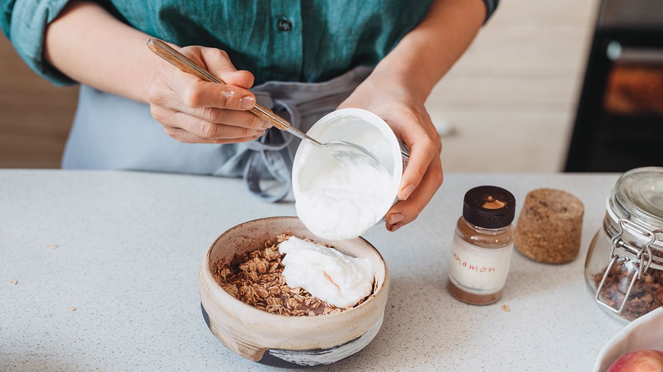 A woman pours yogurt into a bowl