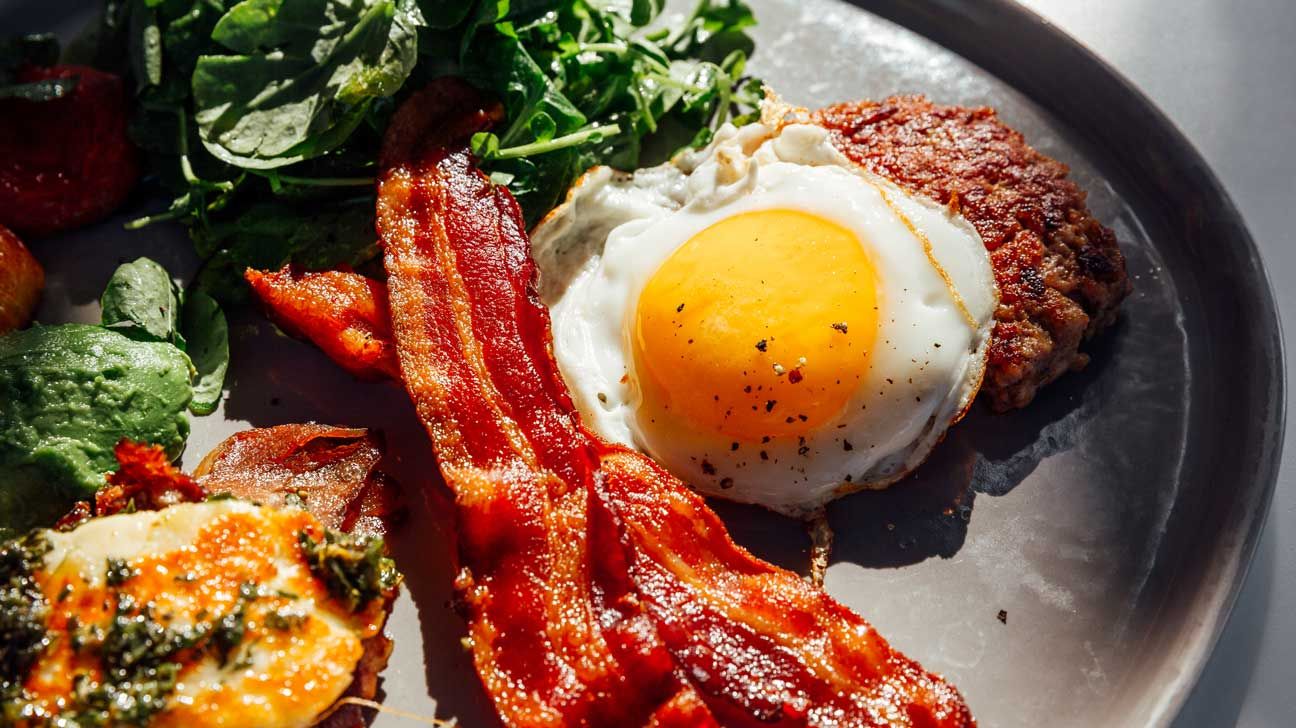 A plate of bacon, eggs, and greens.