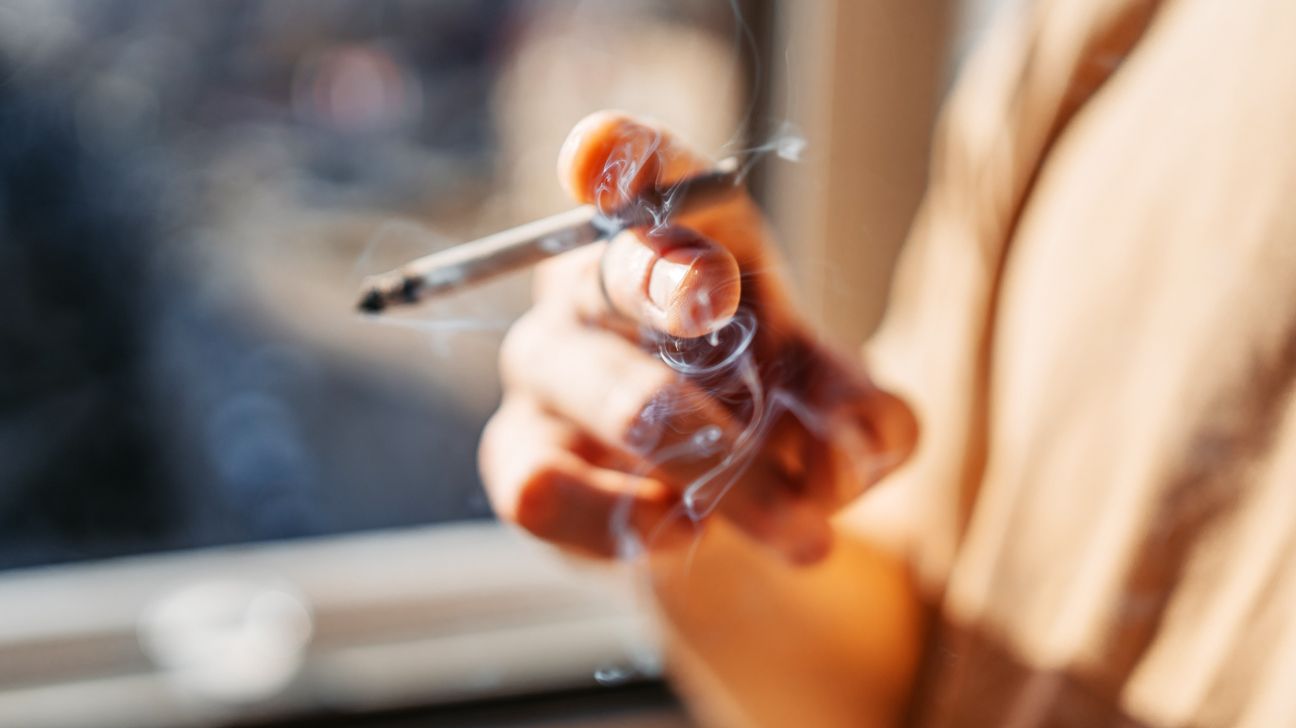 A person holding a lit cigarette.