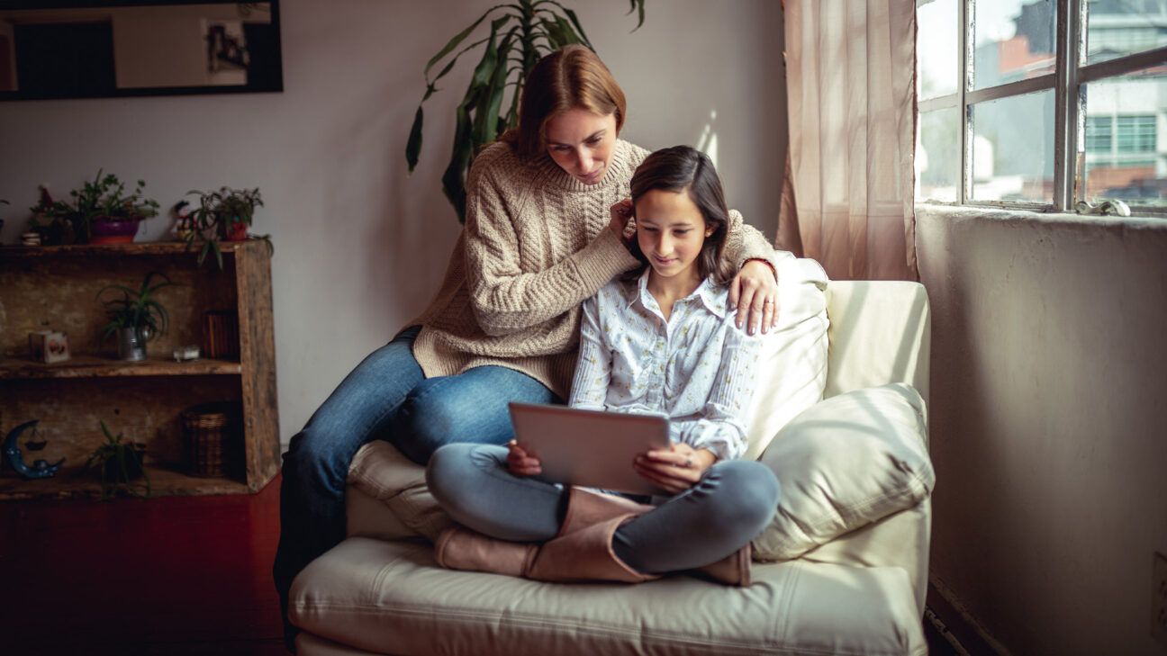 Mother and daughter sitting in a chair with an iPad