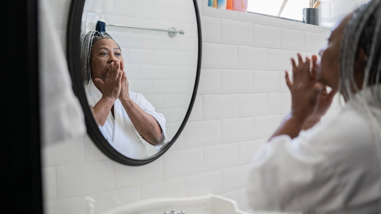 black-woman-washing-face-in-mirror