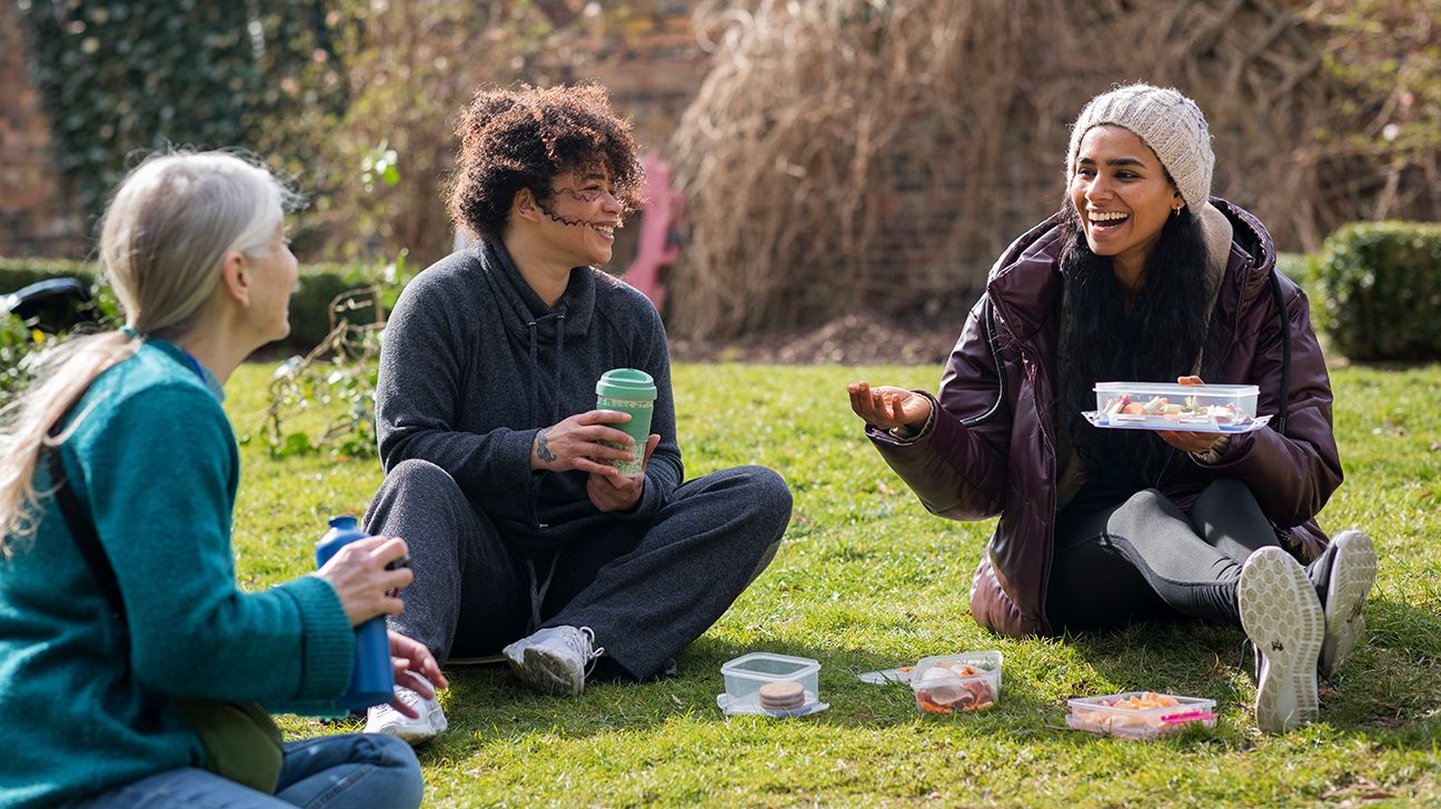 Three friends eating picnic lunch outside