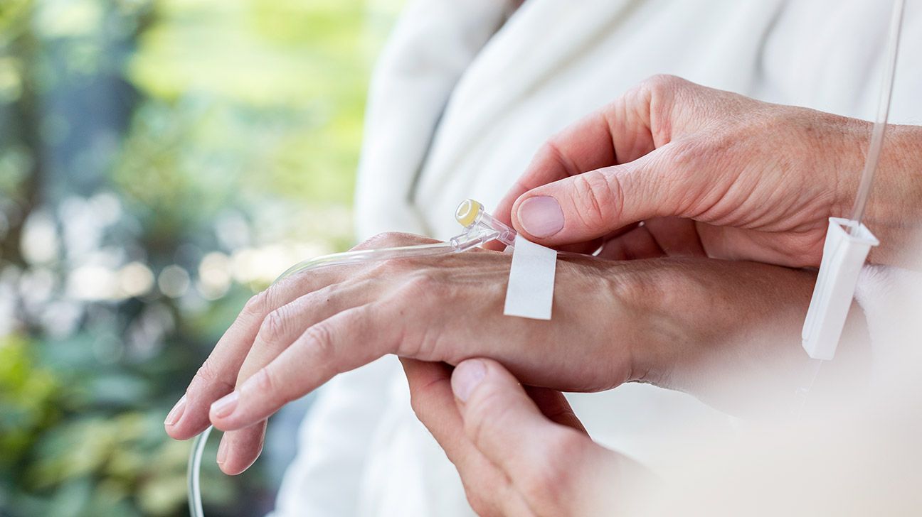 A person taping a cannula to someone's hand.