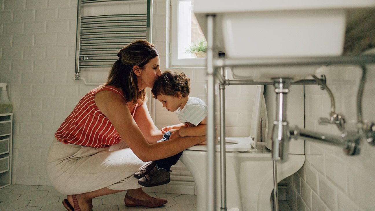 autistic child sitting on toilet with parent comforting them-1