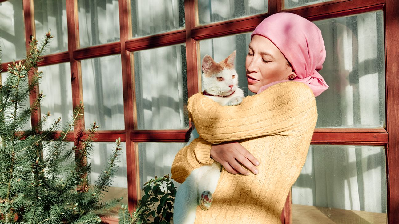 Woman wearing a headscarf holding a cat in her arms