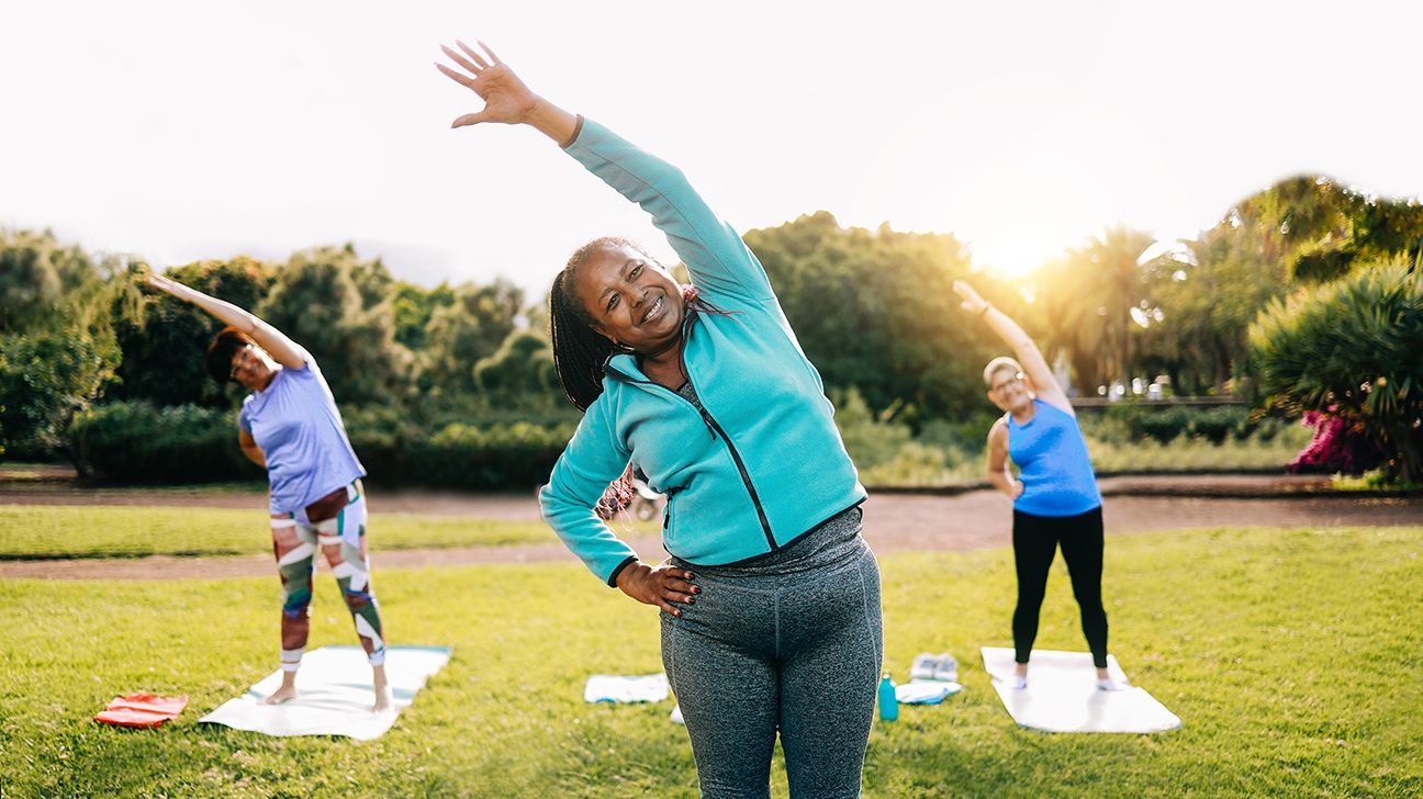 Women exercising and stretching outdoors, in a park