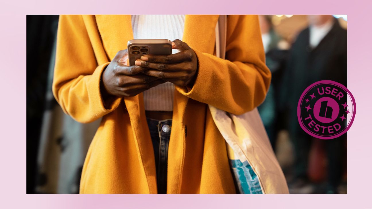 person wearing a yellow coat is walking but looking down at their phone. There is a Healthline &quot;User Tested&quot; badge on the middle right of the image