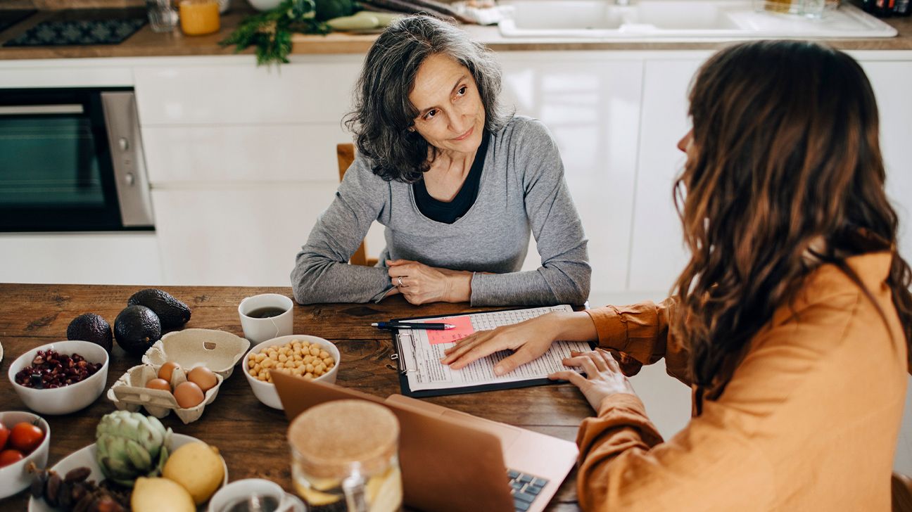 A female dietitian discusses food items with an older woman