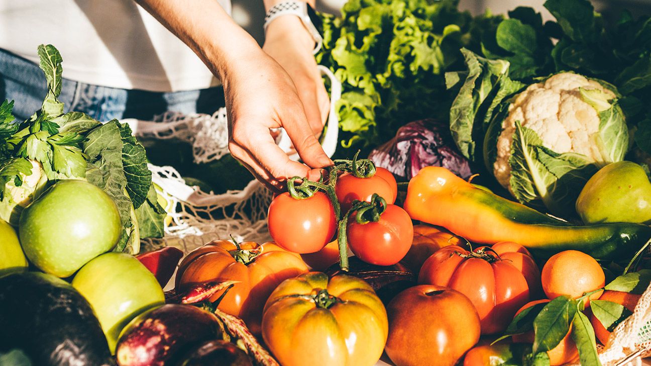 A close up image of hands touching tomatoes and lettuce