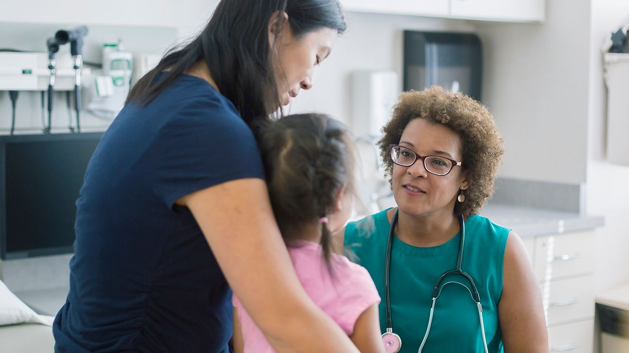 doctor talking with a parent and child in a medical exam room