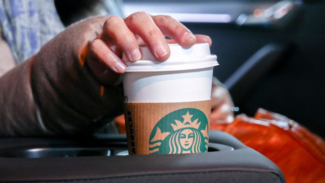 A person holding a Starbucks coffee cup.