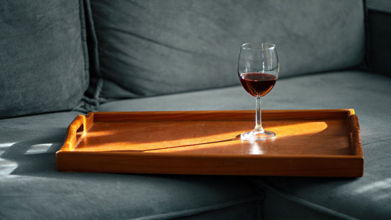 A glass of wine on a tray on a sofa